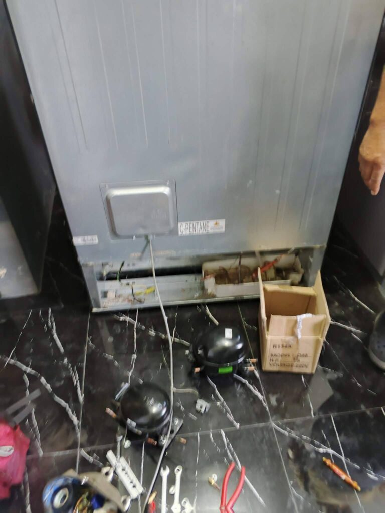 Refrigerator repair service in Santa Cruz. Technician inspecting the compressor and tools for appliance repair in a local home