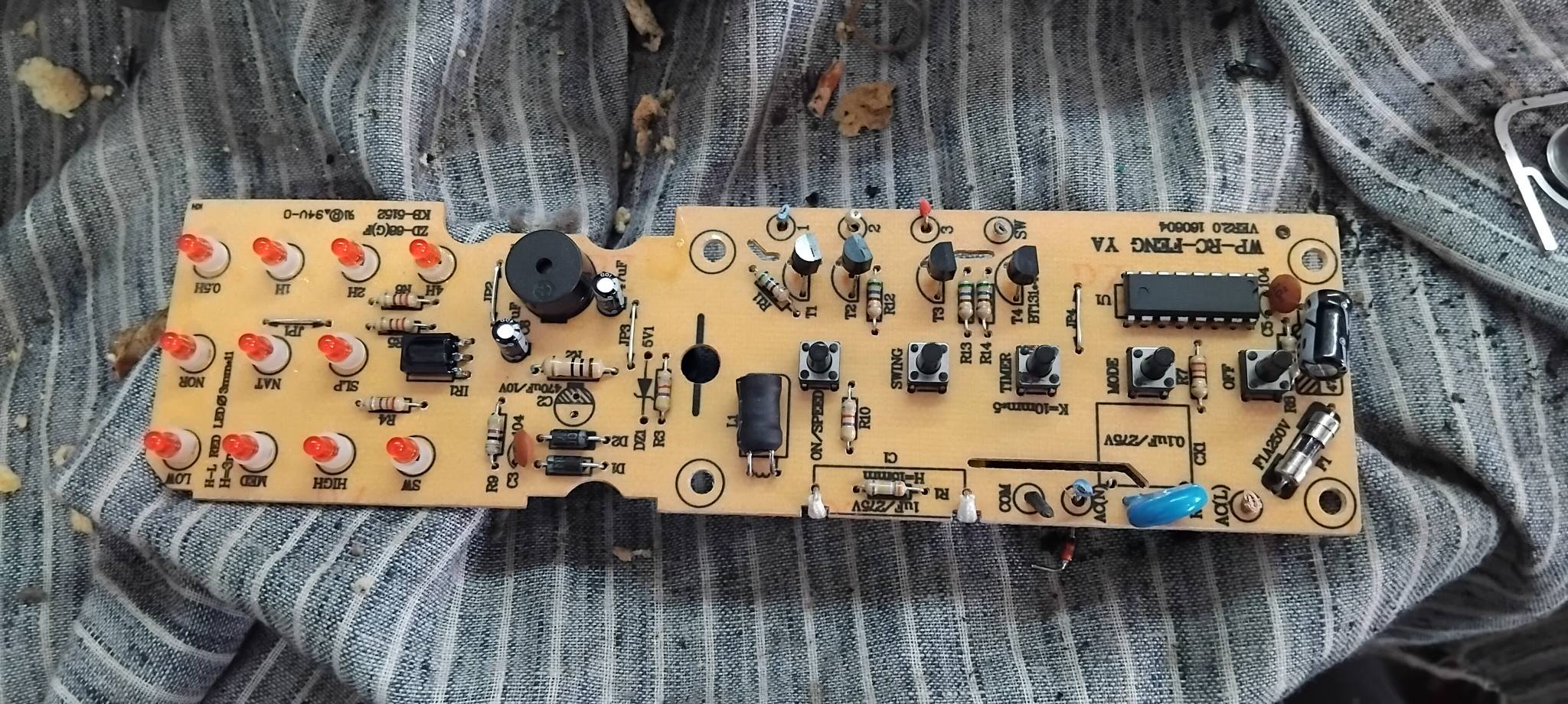 Detailed view of an appliance circuit board with visible electrical components, being examined during a repair.