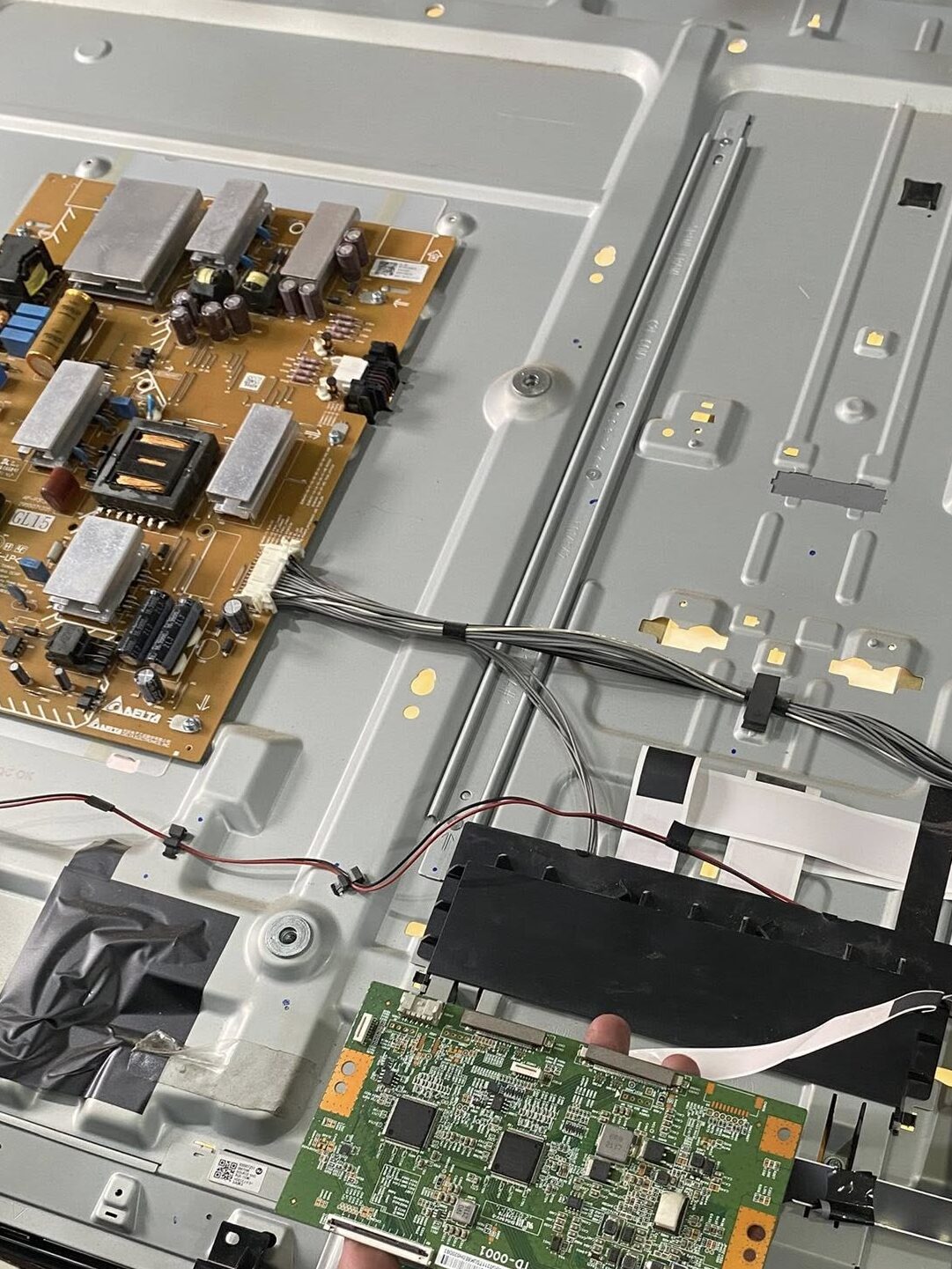 Close-up of an appliance circuit board showing electrical components and connections during a repair process.