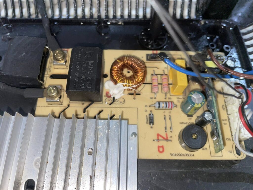Technician inspecting an appliance circuit board for repair, focusing on electrical components in a workshop.